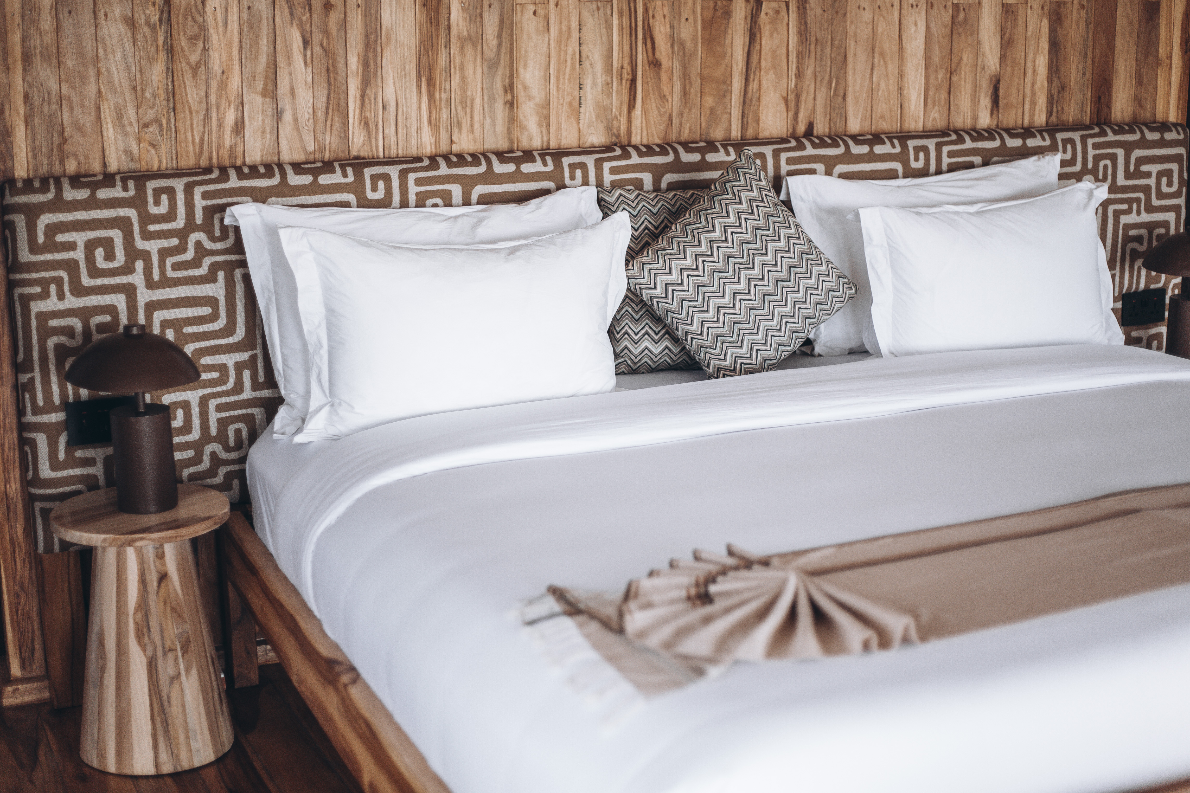 Luxury king bed with African patterned headboard at Conserve Safari Serengeti