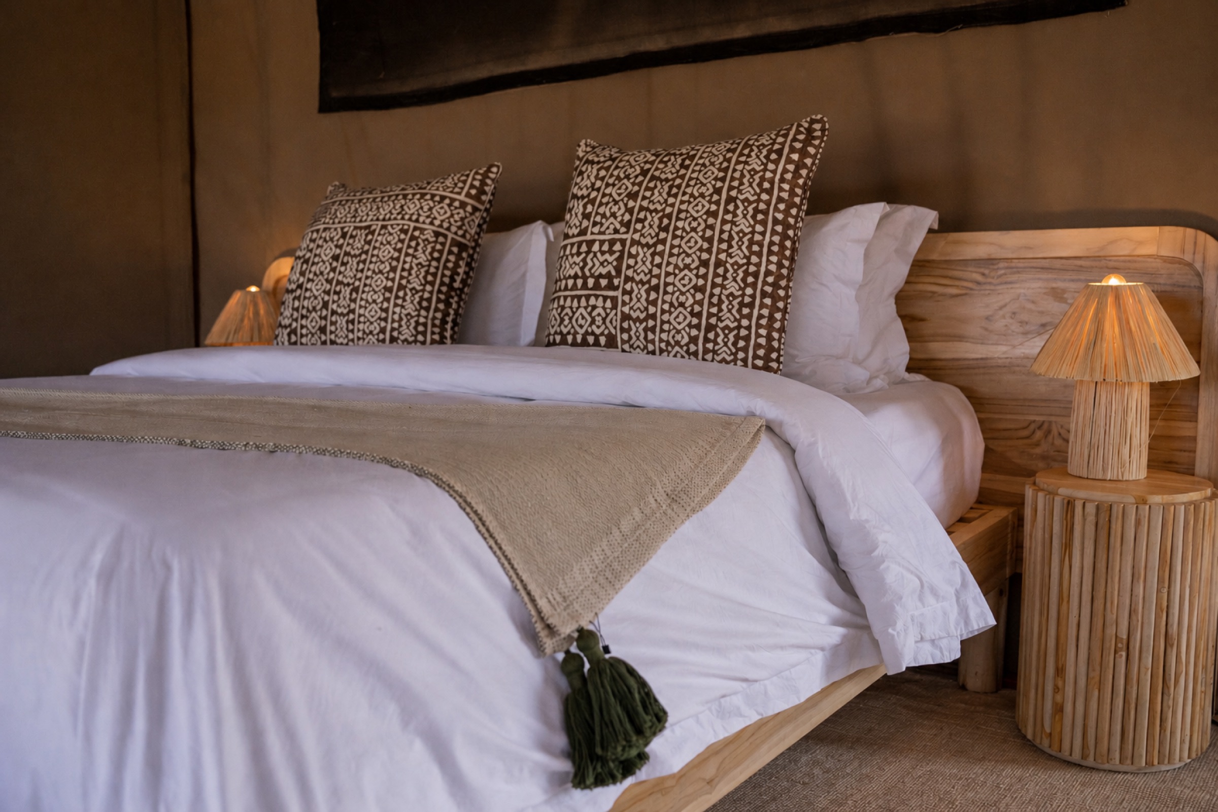 Luxury king bed with African cushions and linen throw at Conserve Safari Tarangire